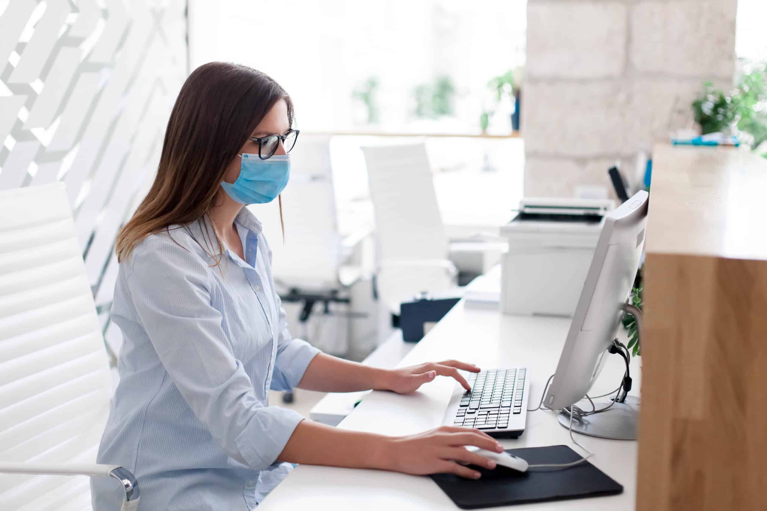 Young woman wearing medical mask in office.