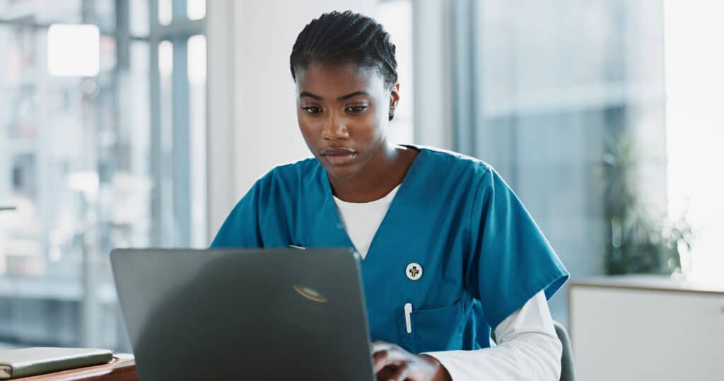 Hospital, nurse and black woman with laptop, typing and thinking with research, online reading and internet. African person, medical or professional with computer, doctor and digital app with email.
