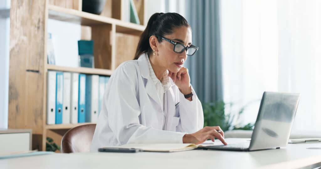 Research, woman and doctor with laptop in hospital for medical report or diagnostic information. Thinking, computer and female healthcare worker with brainstorming for treatment plan in clinic office.