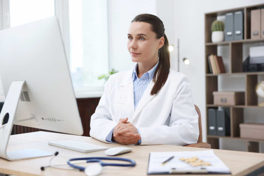Doctor having online consultation via computer in clinic