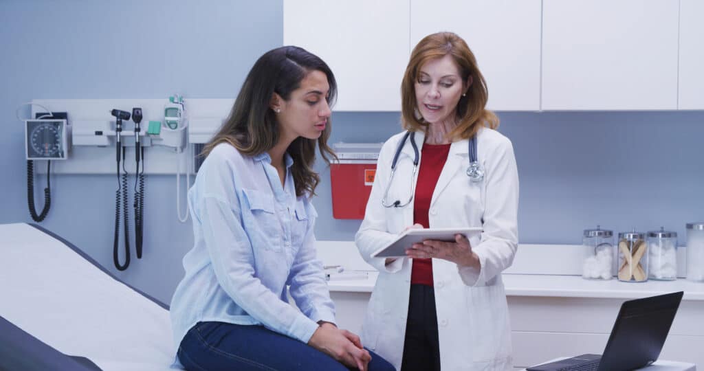 Lovely young latina patient consulting with doctor about health condition