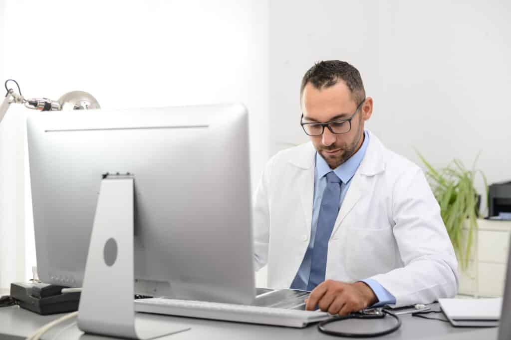 How Automated Appointment Reminder Software Reduces No-Shows portrait of a handsome man male doctor in medical practice office working on computer