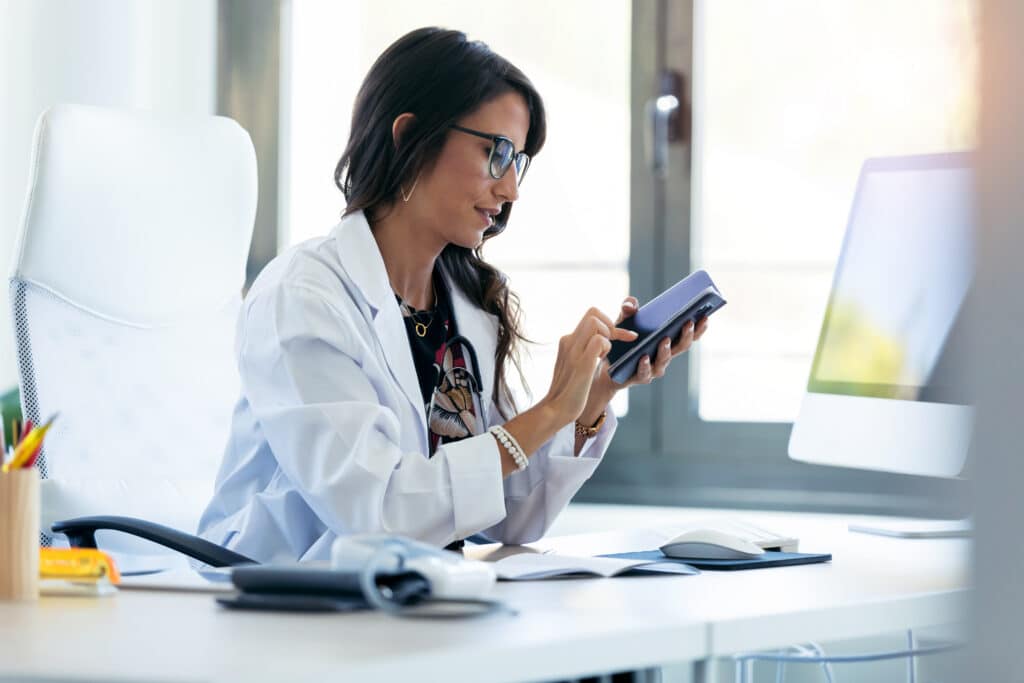 How Automated Appointment Reminder Software Reduces No-Shows Shot of pretty young woman gynecologist using her mobile phone before starting consultation in the clinic.