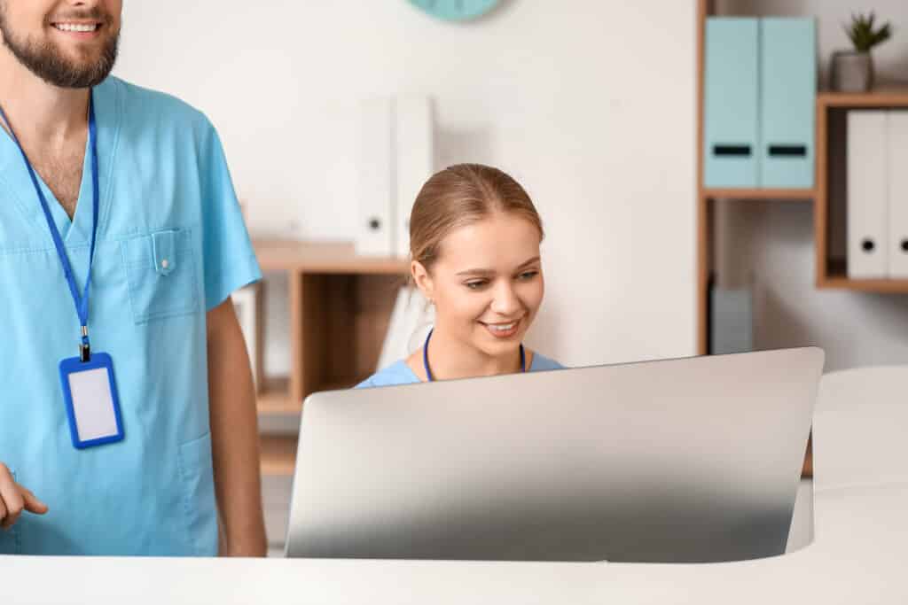 Male and female receptionists working at desk in clinic