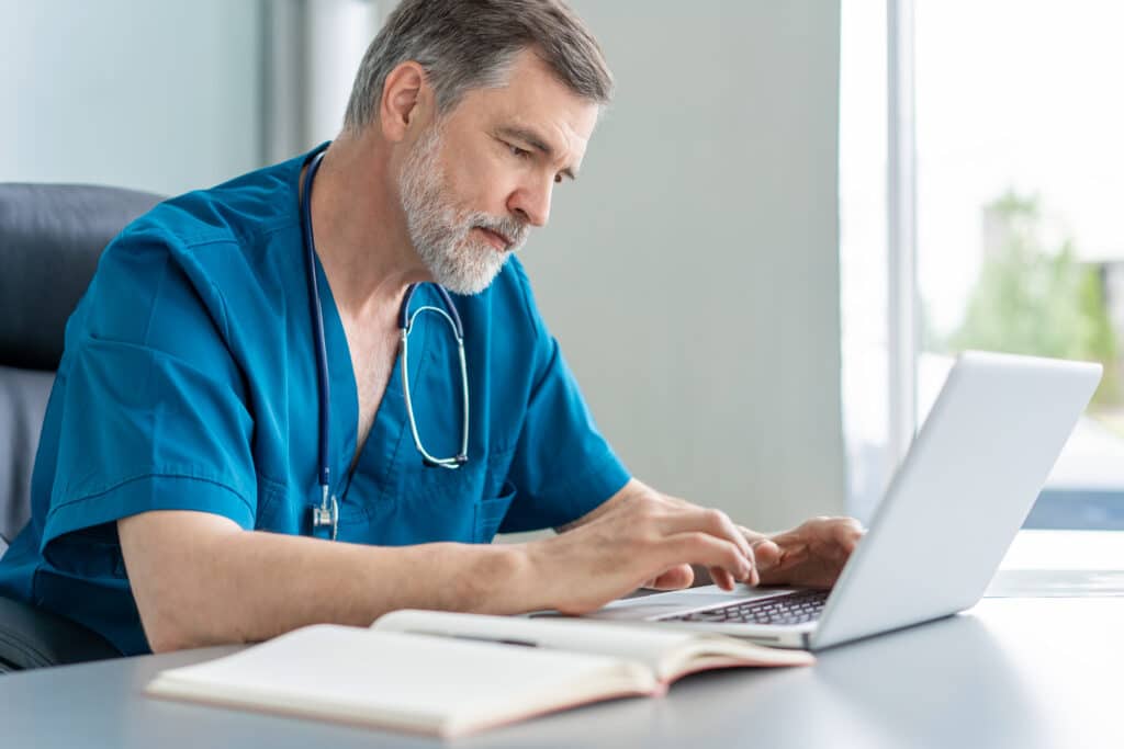 How AI Document Analysis Improves Efficiency Mature male doctor working on laptop computer, sitting in medical office