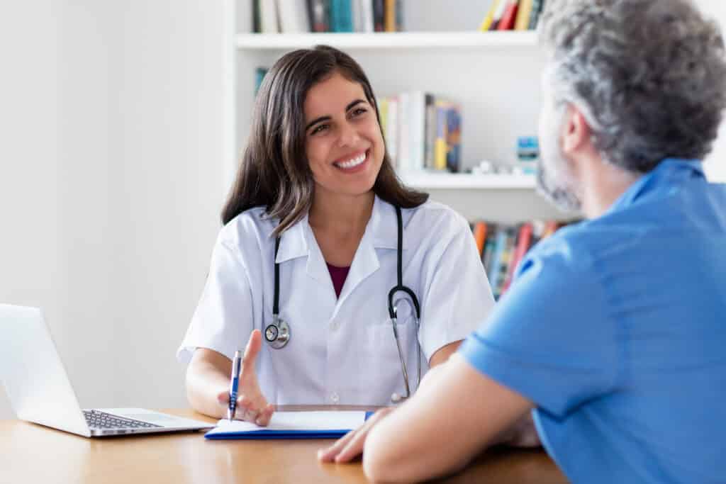 Laughing Hispanic female doctor talking with patient at hospital