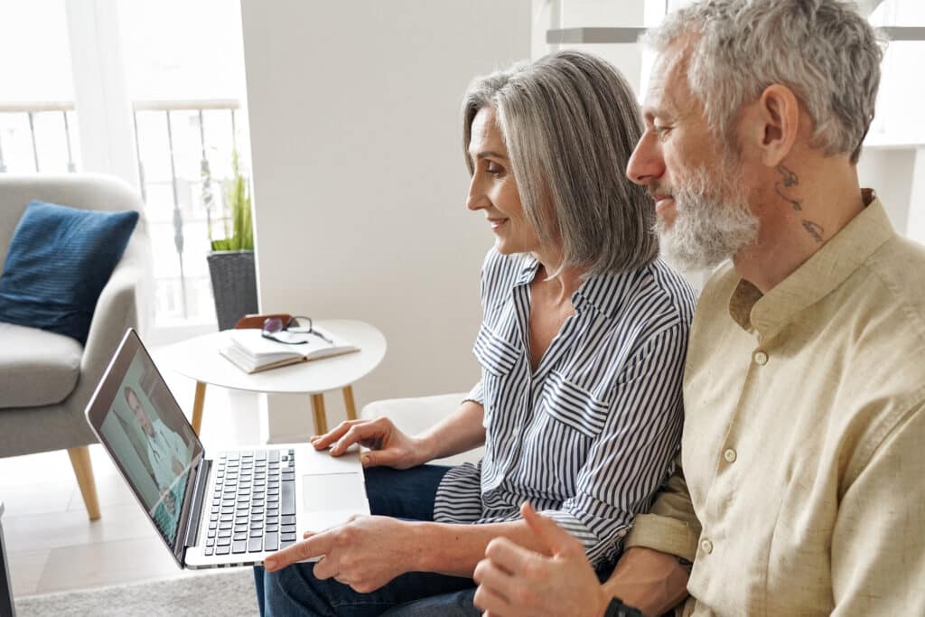 Why HIPAA-Compliant Telehealth Is Vital for Your Practice Senior mature family couple getting online telemedicine call consultation with virtual doctor using laptop computer sit on couch at home. Grandparents ehealth, older patients telehealth consultation.