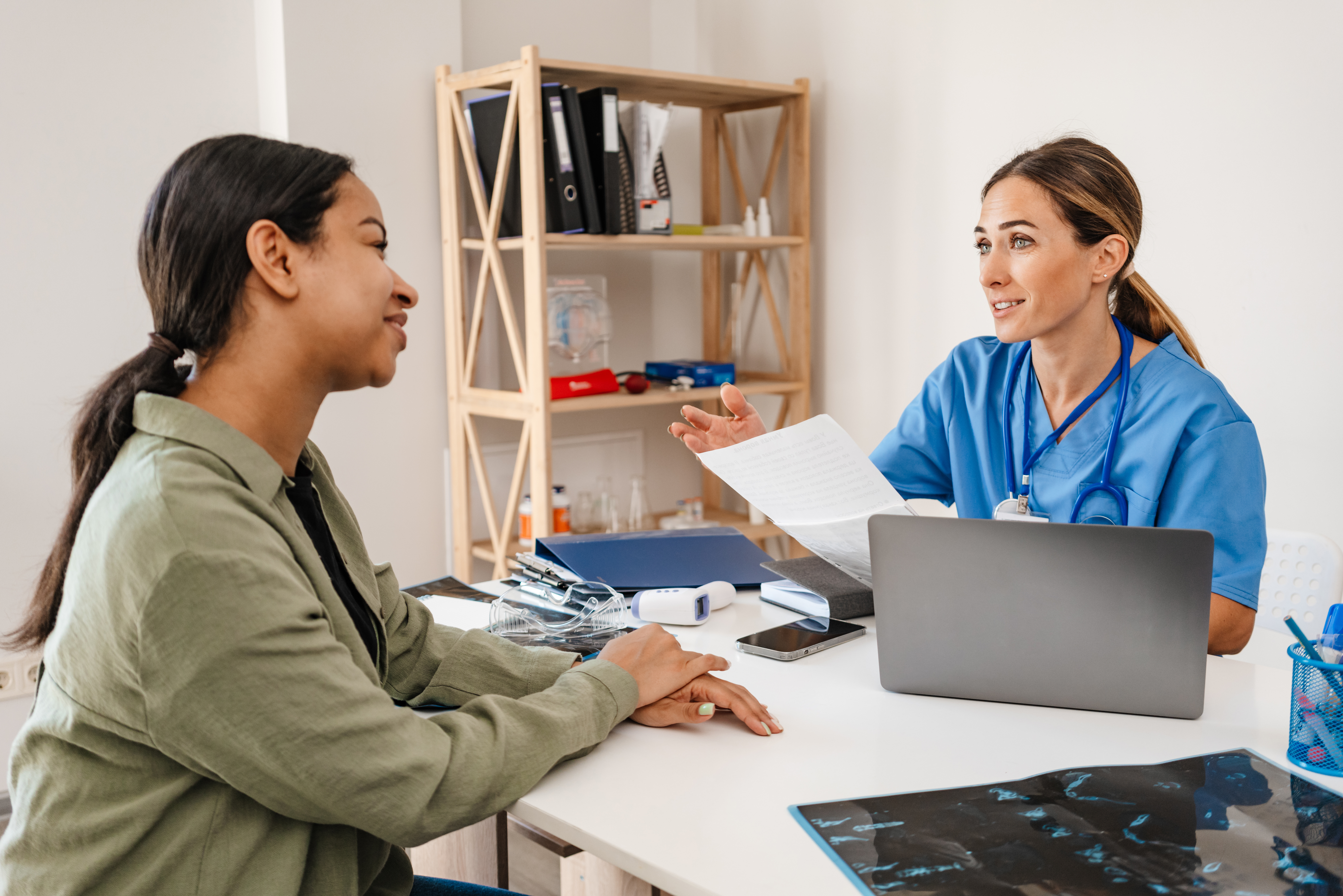 White woman doctor talking with patient while working in her office indoors