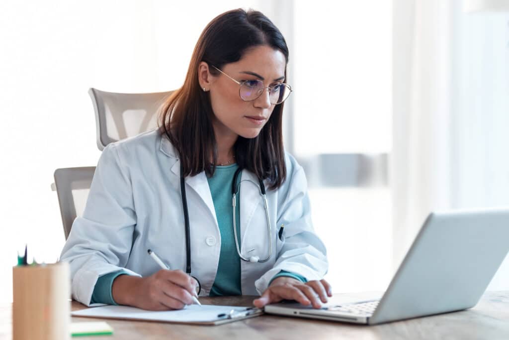 Shot of attractive female doctor working with her computer in medical consultation.