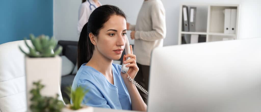 Female receptionist talking by phone in clinic