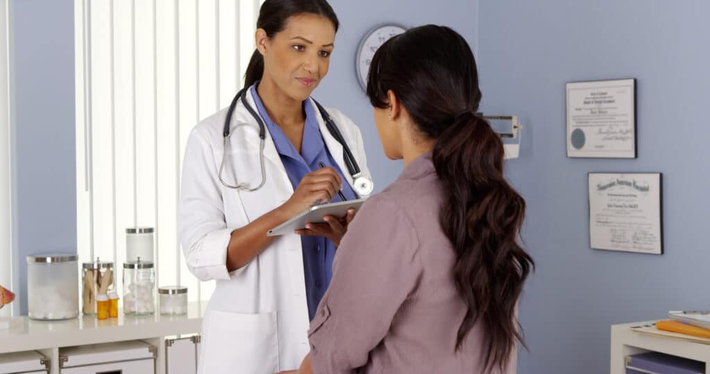 emale doctor reviewing test results with female patient in exam room
