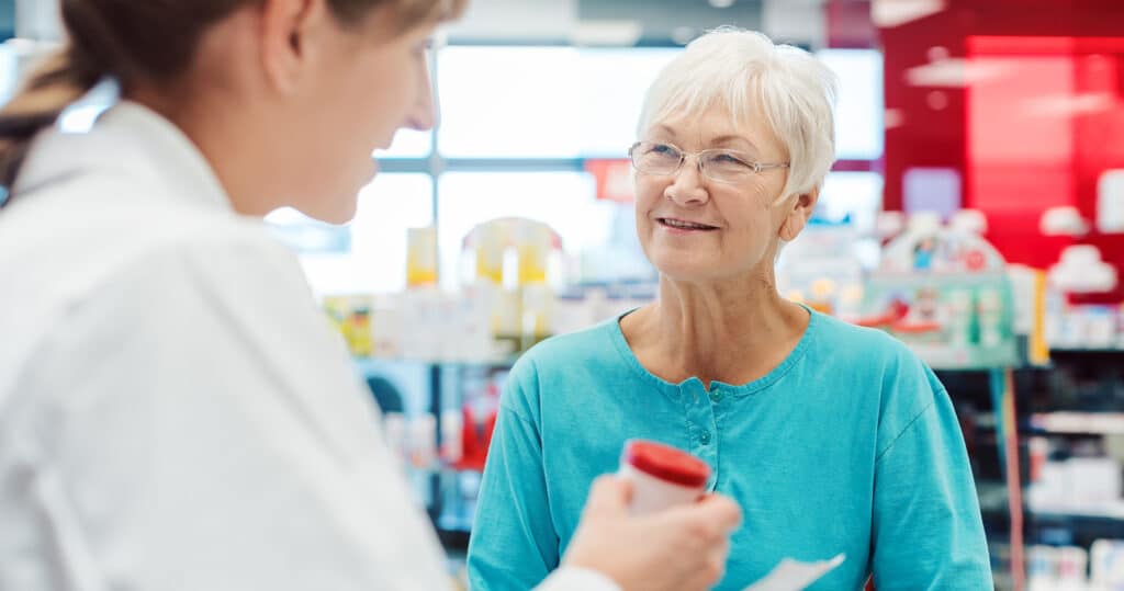 A satisfied patient picking up their medication quickly from a pharmacy using a paperless system